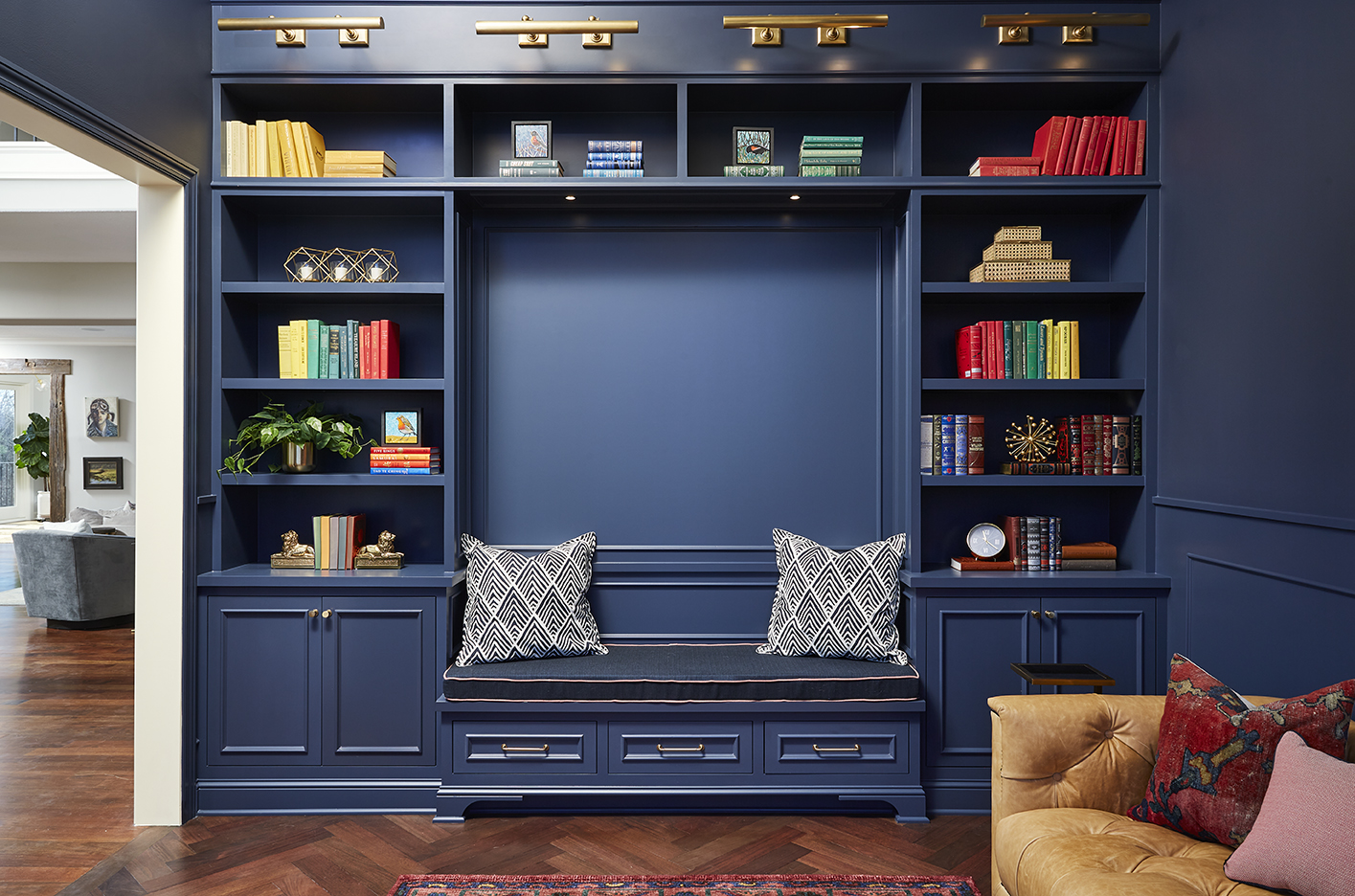 A blue living room with a bench and bookshelves.