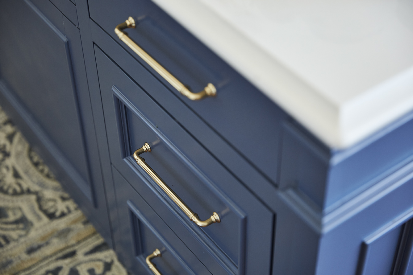 A close up of a blue bathroom vanity with gold handles.