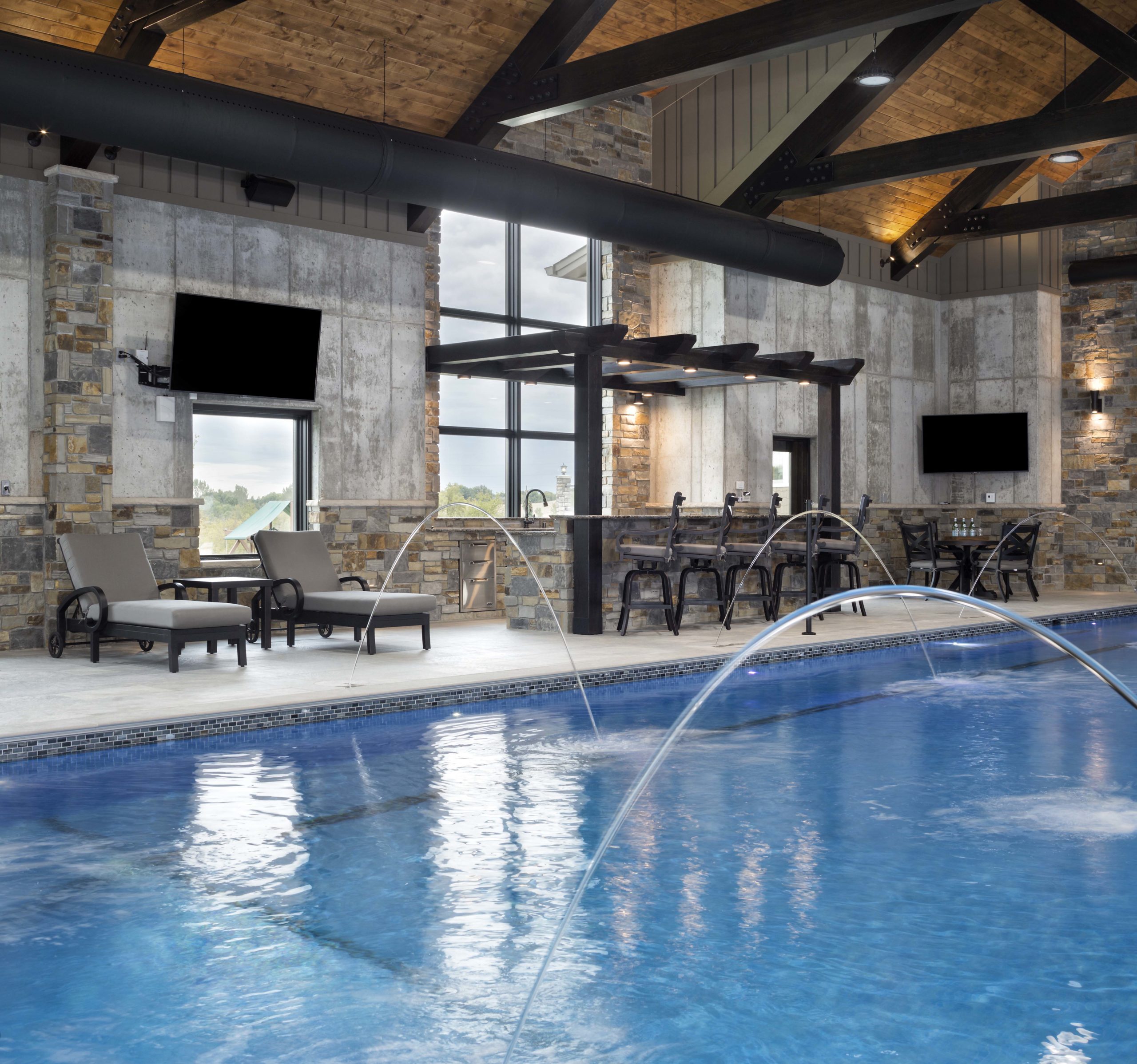 An indoor swimming pool with a waterfall and lounge chairs.