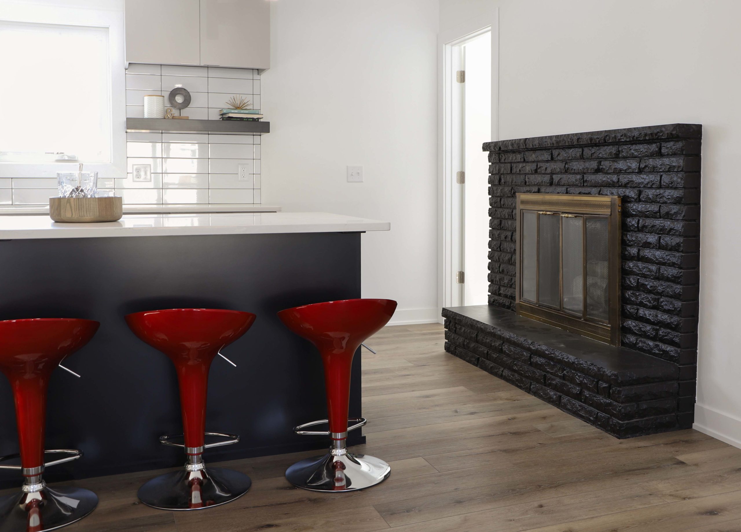 A kitchen with red stools and a fireplace.