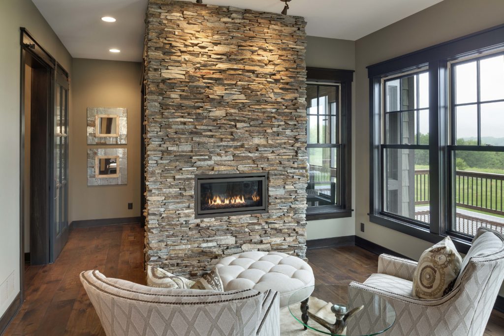 A living room with a stone fireplace and chairs.