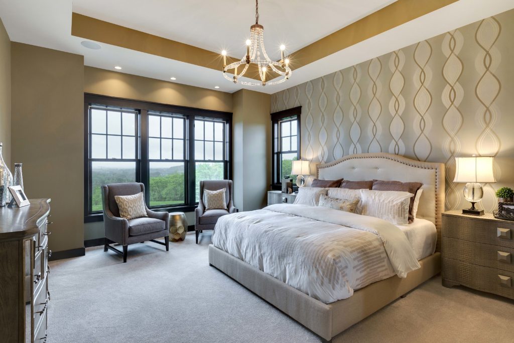 A bedroom with beige walls and a chandelier.