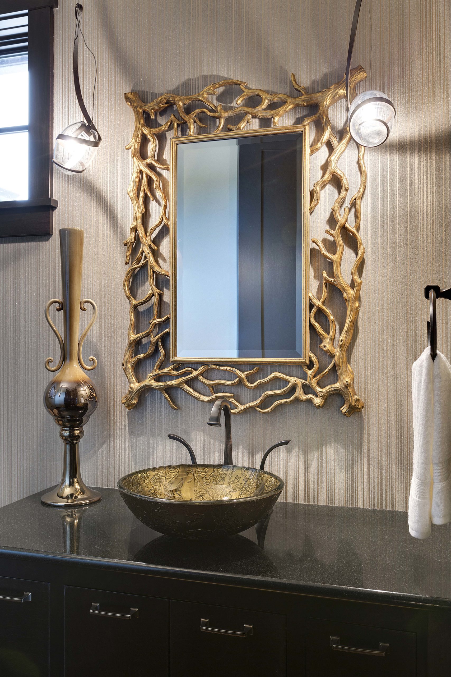 A bathroom with a black sink and a gold mirror.