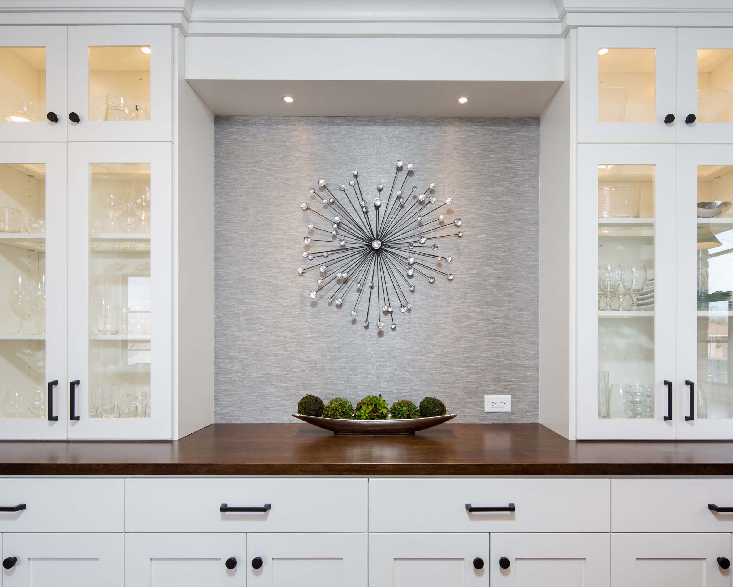 A white kitchen with a clock on the wall.