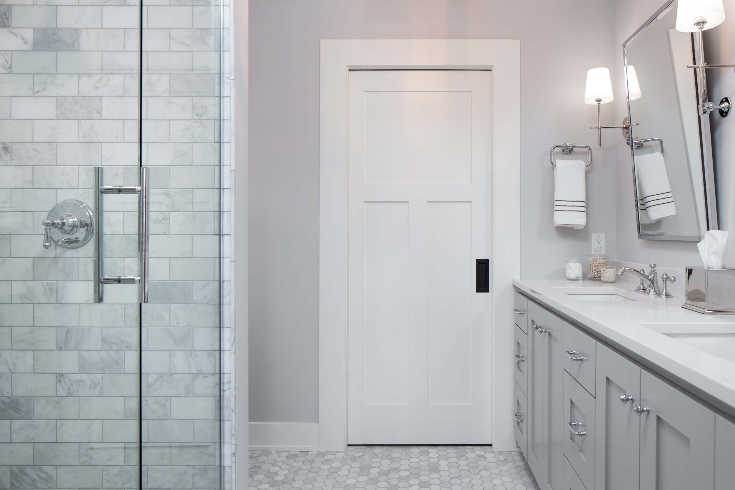 A white and gray bathroom with a glass shower door.