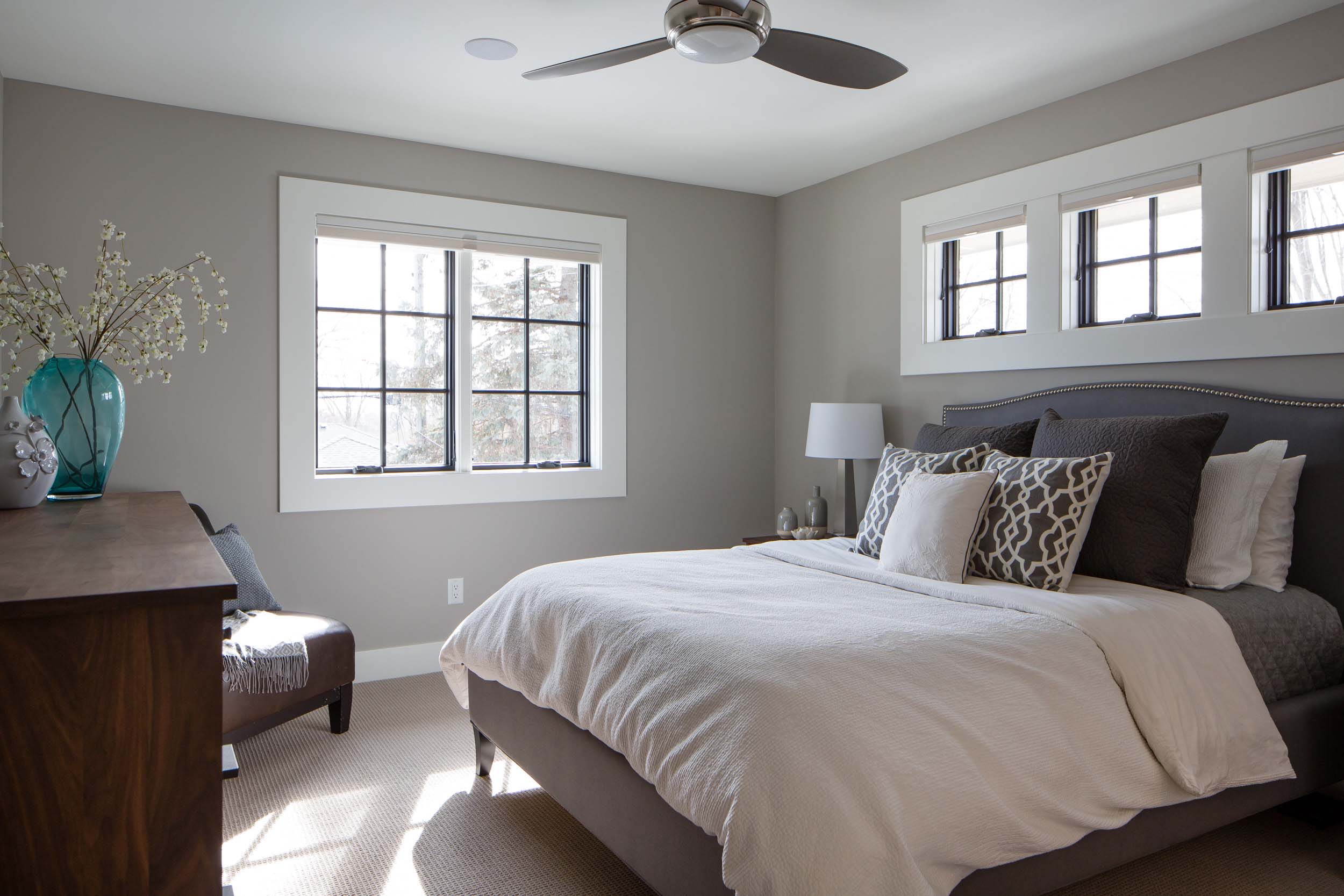 A bed in a bedroom with gray walls and a ceiling fan.