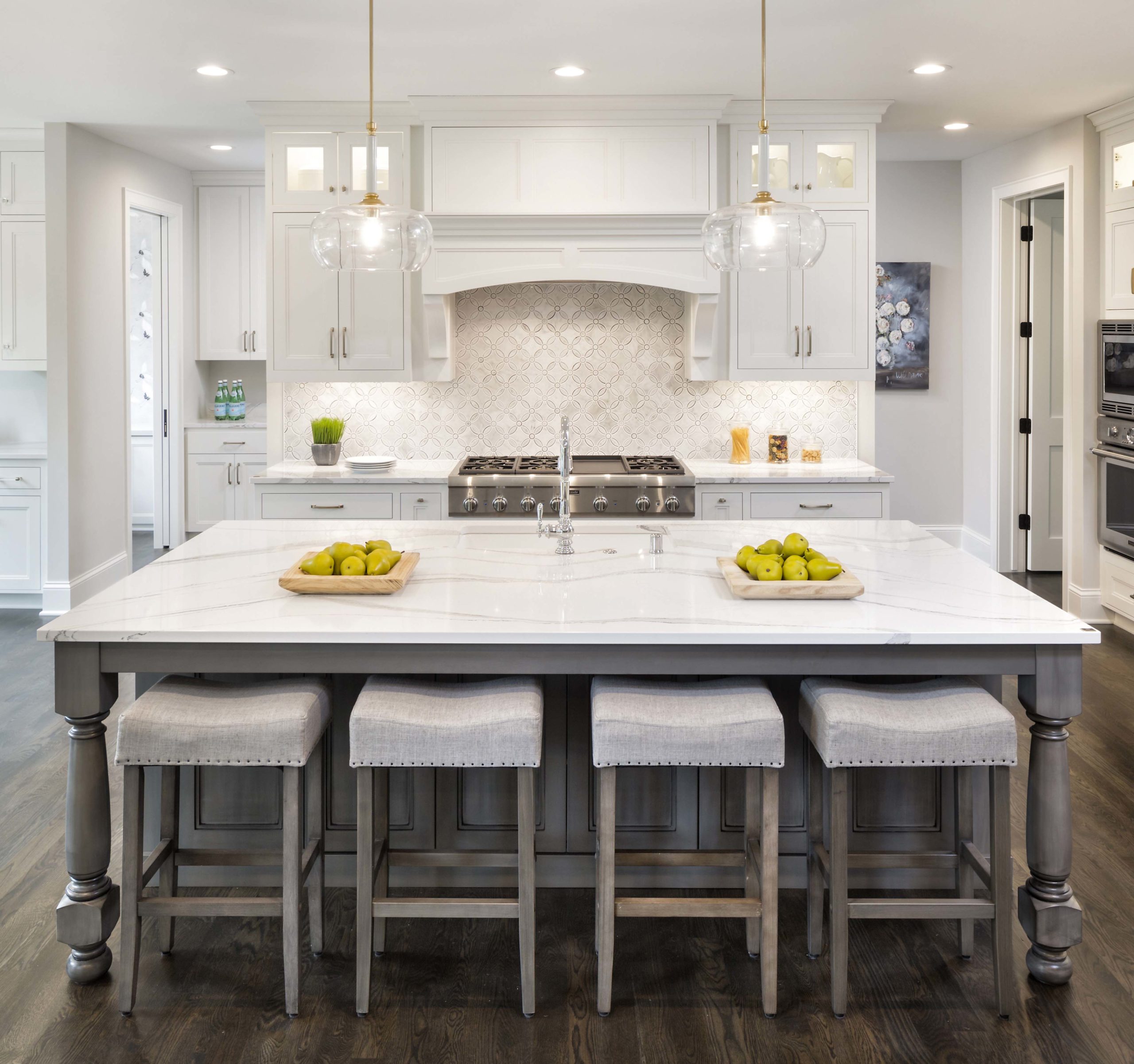 A white kitchen with a center island and stools.