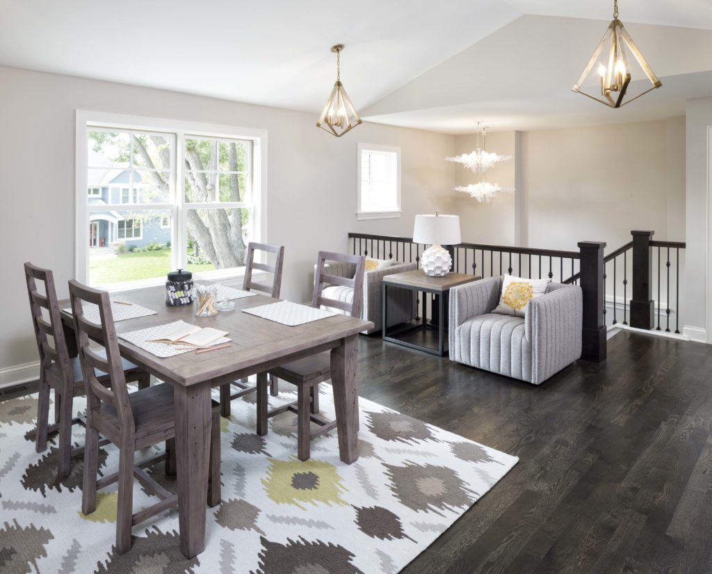 A dining room with hardwood floors and a gray rug.