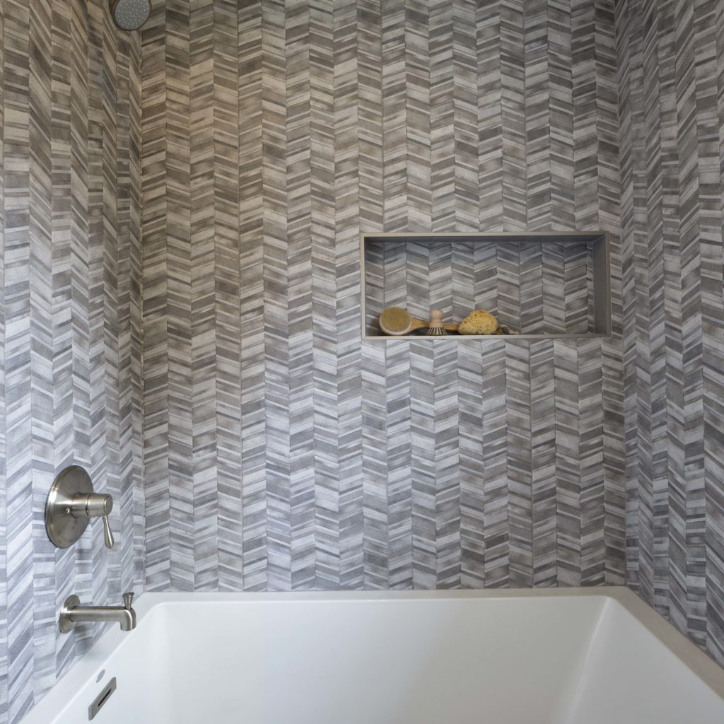 A bathroom with tiled walls and a bathtub.