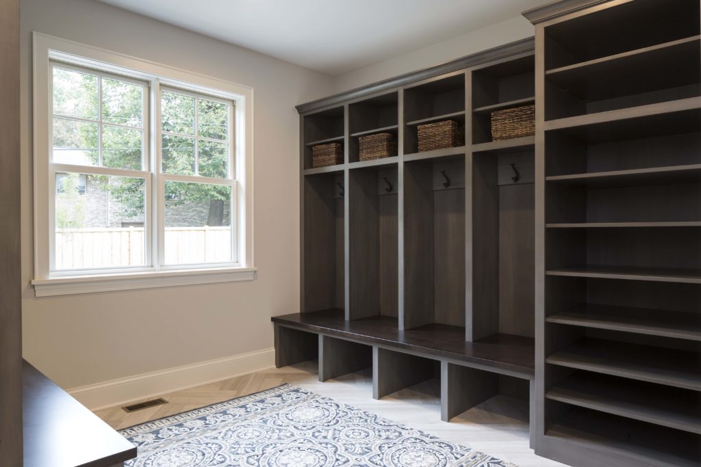 A mudroom with shelves and a rug.