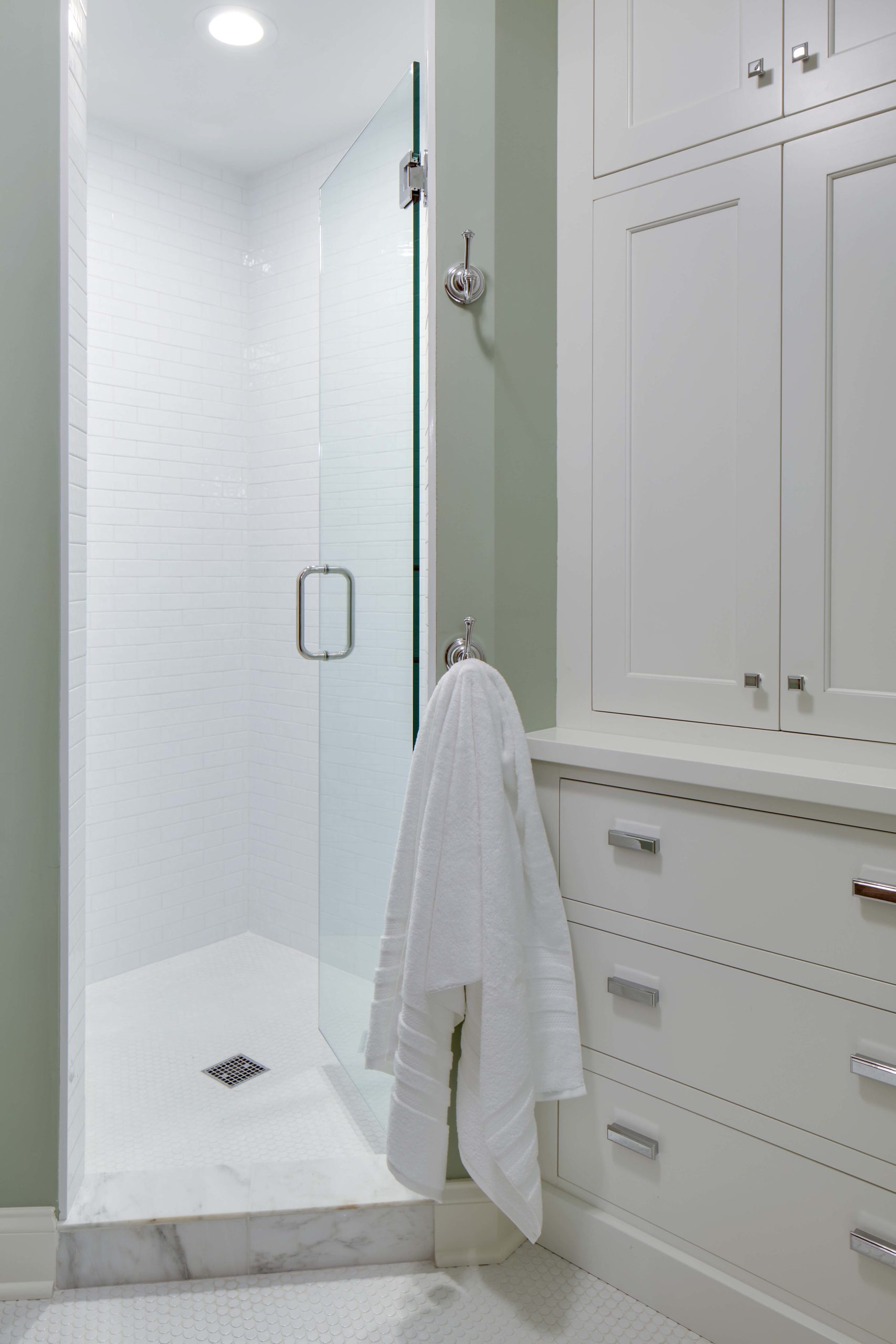 A white and green bathroom with a glass shower stall.