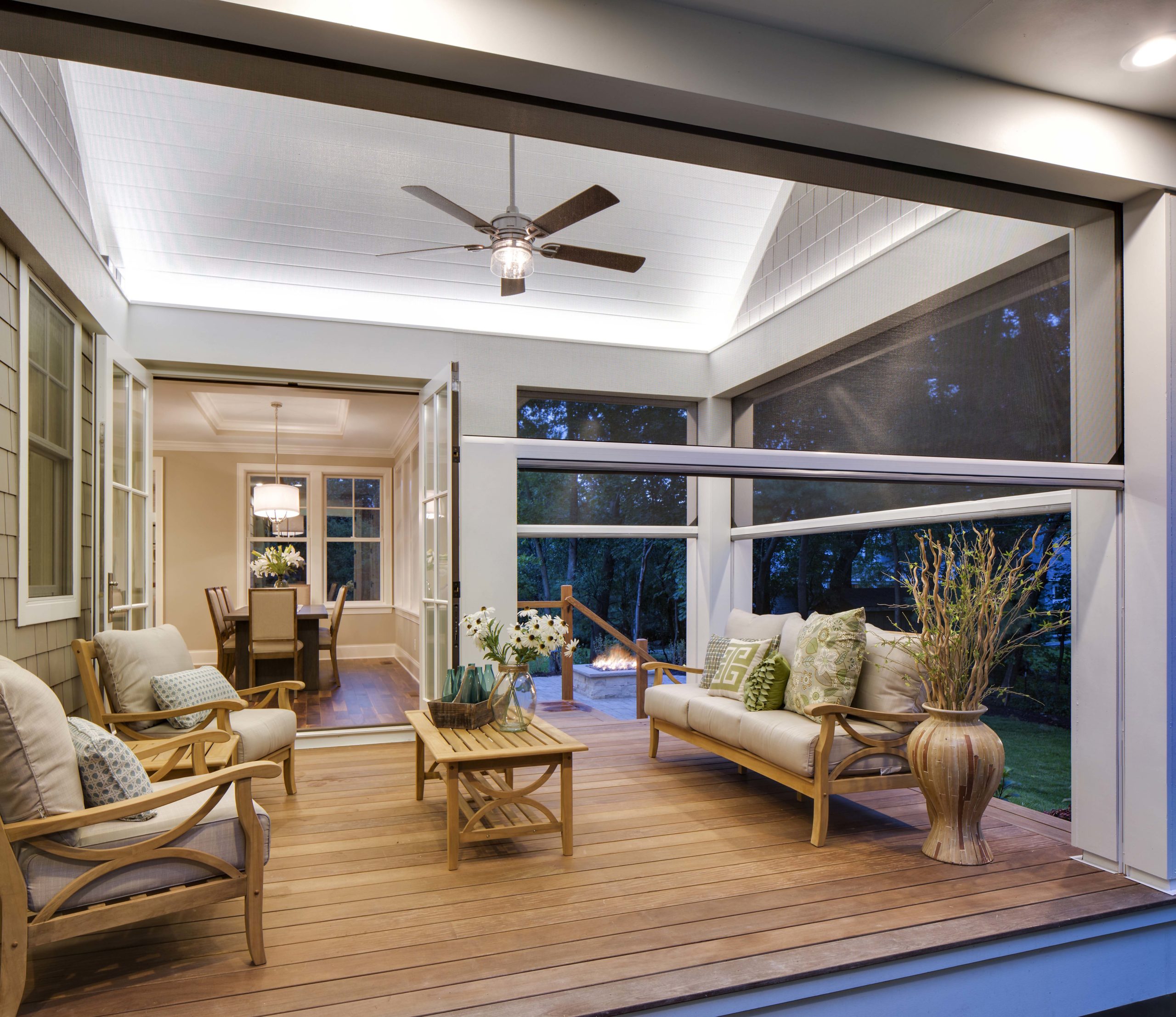 A screened in porch with furniture and a ceiling fan.