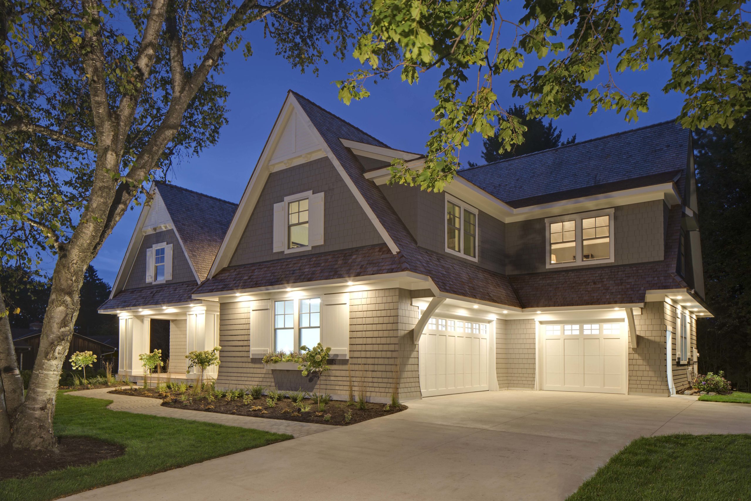 A home with two garages and a driveway at night.