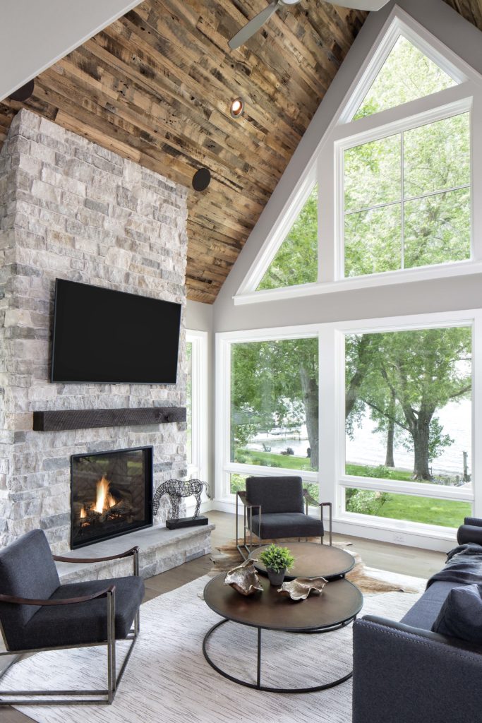 A living room with a stone fireplace and large windows.