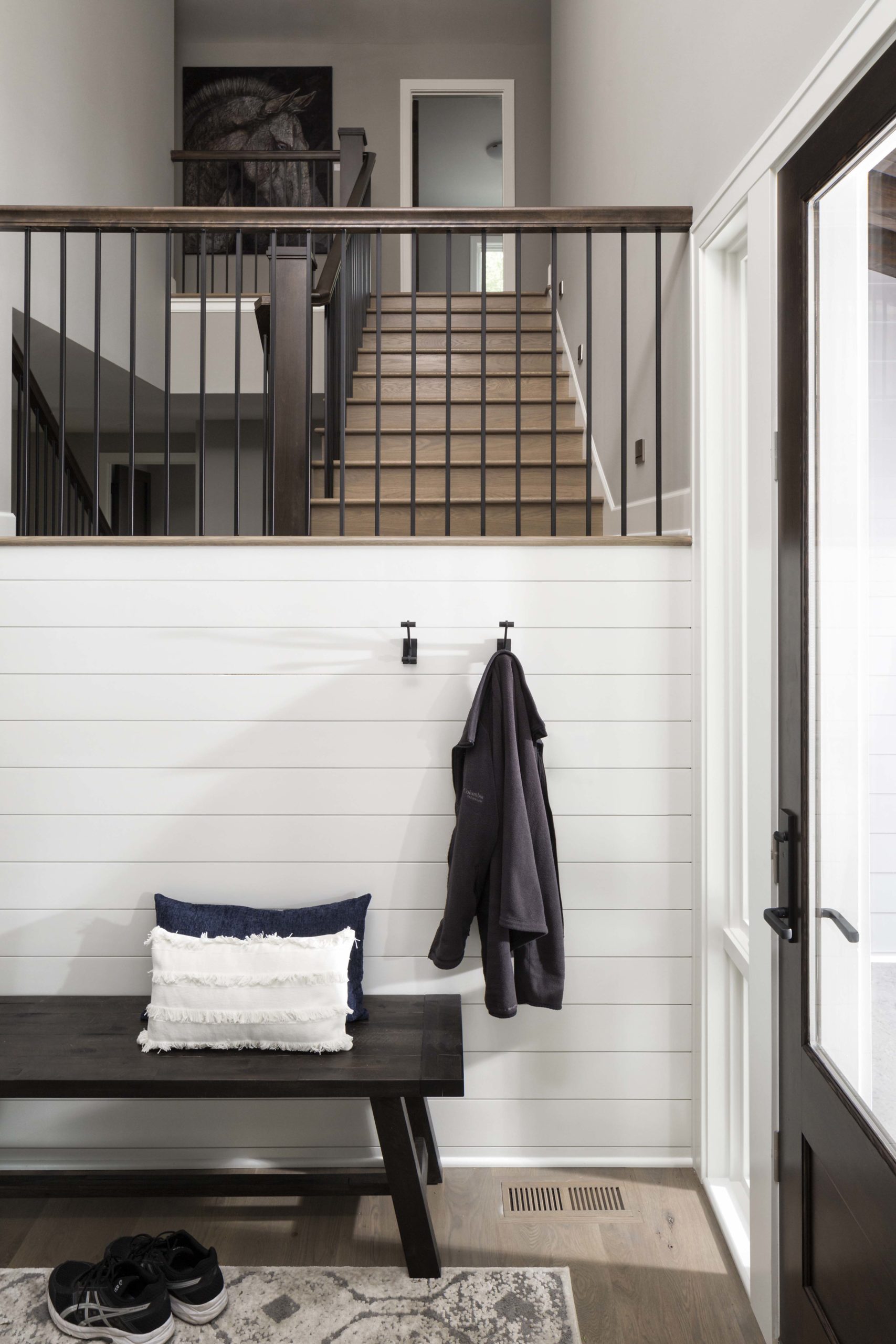 An entryway with a bench and stair railing.