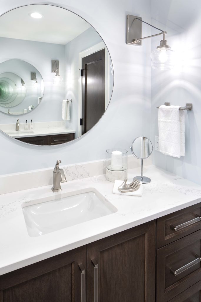 A bathroom with a round mirror over the sink.