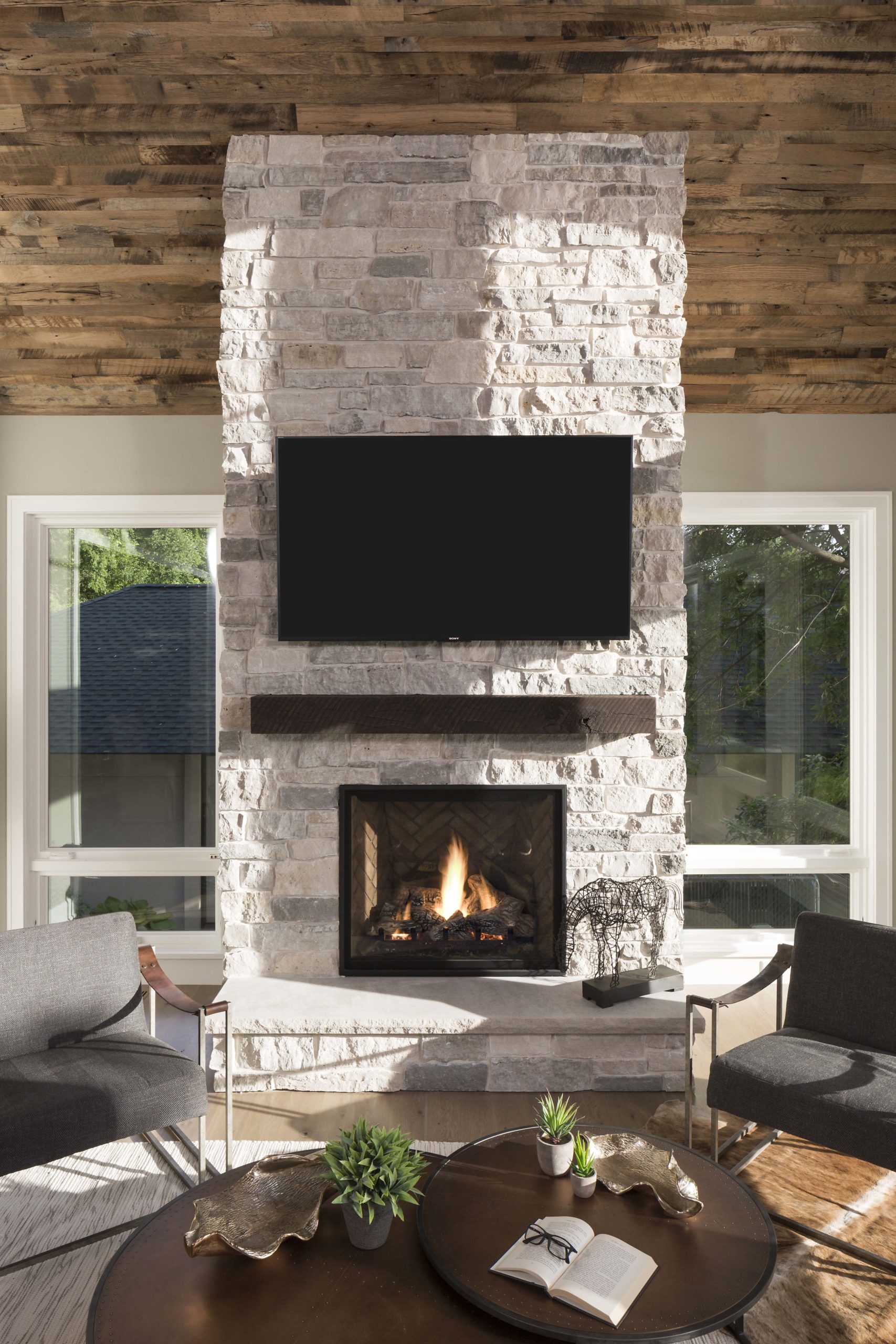 A modern living room with a stone fireplace and tv.