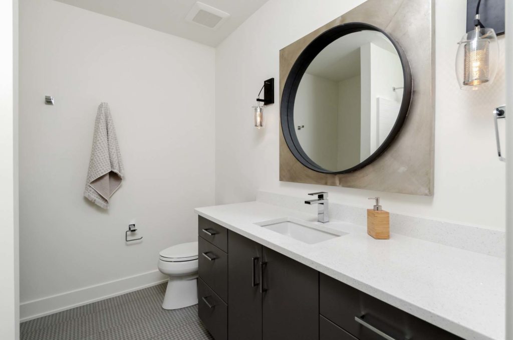 A bathroom with a round mirror and sink.