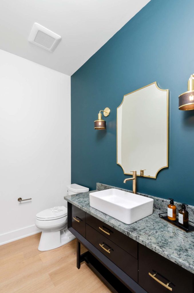 A bathroom with blue walls and a gold vanity.