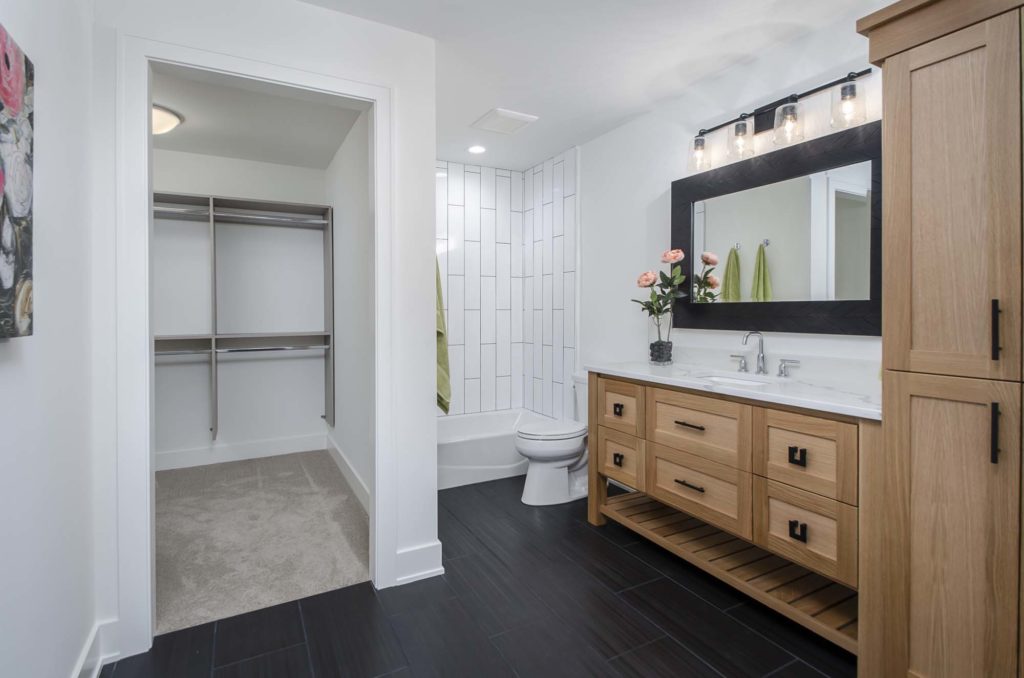 A bathroom with a white vanity and wood cabinets.