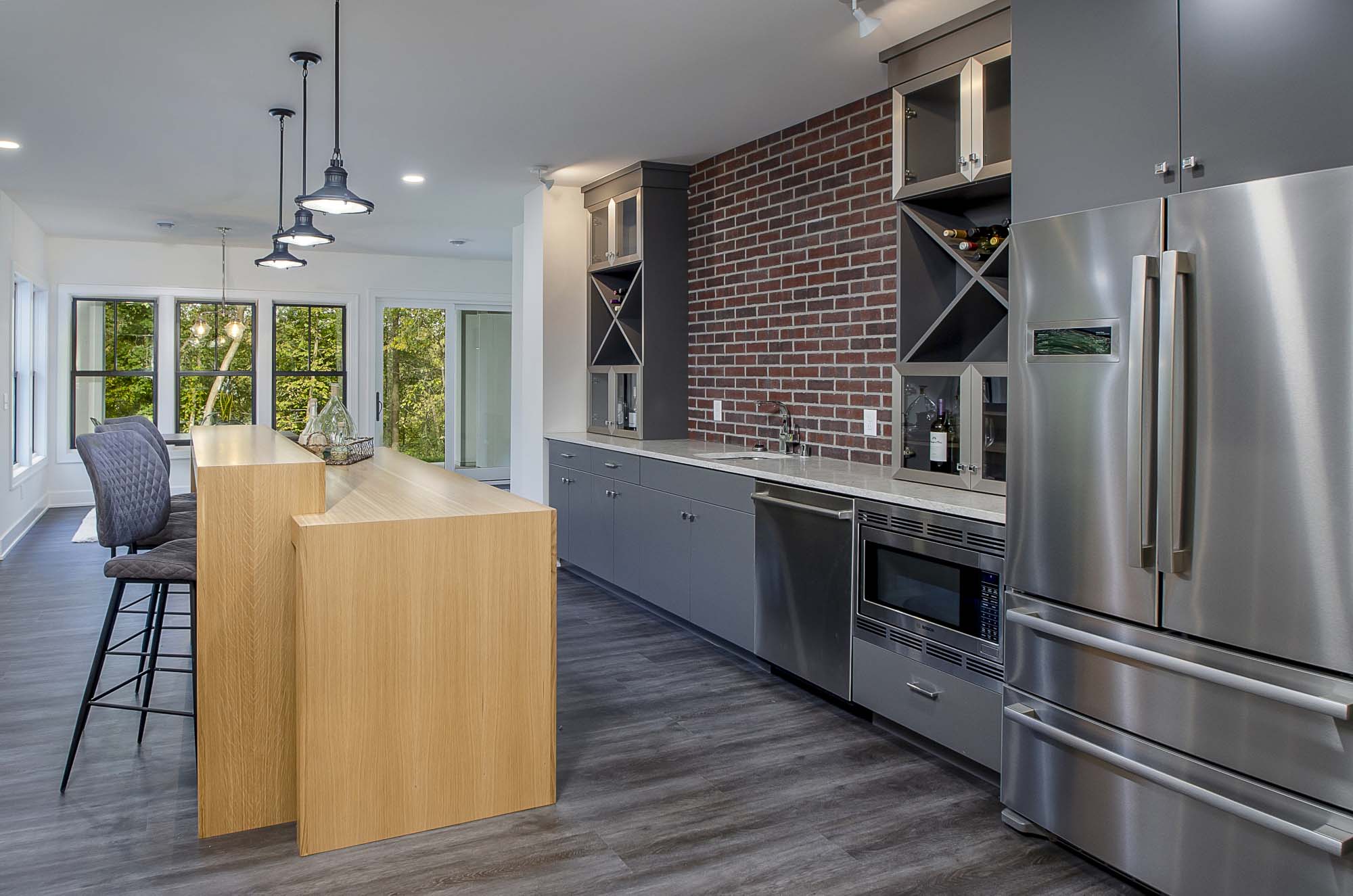 A modern kitchen with stainless steel appliances and a brick wall.