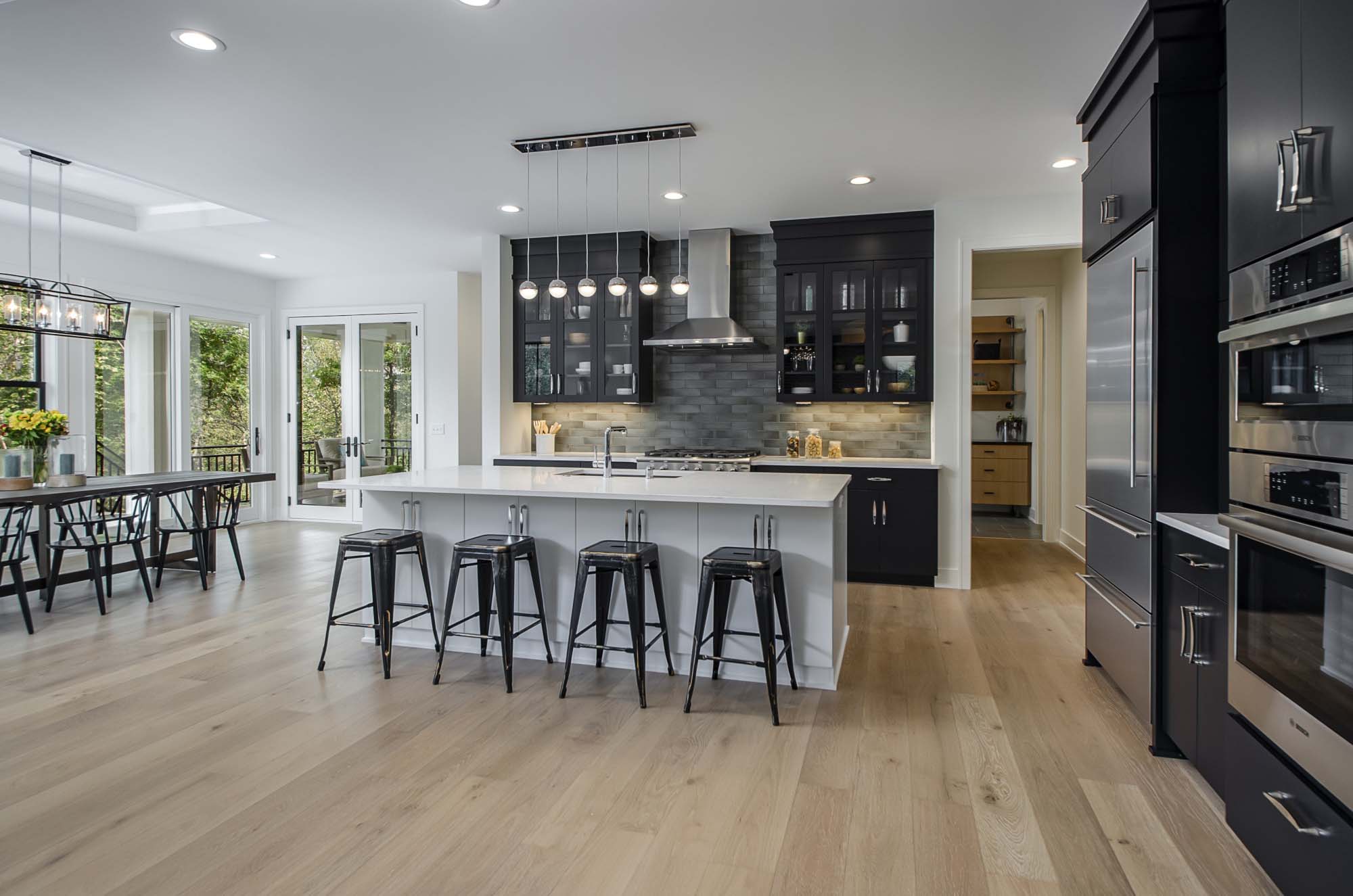 A modern kitchen with black cabinets and hardwood floors.
