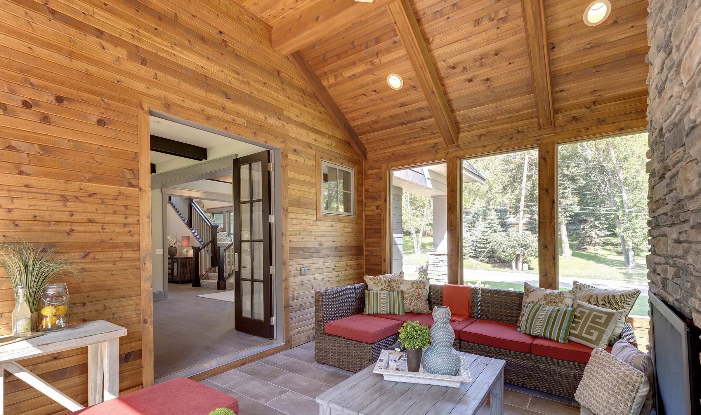 A screened in porch with wood walls and a fireplace.