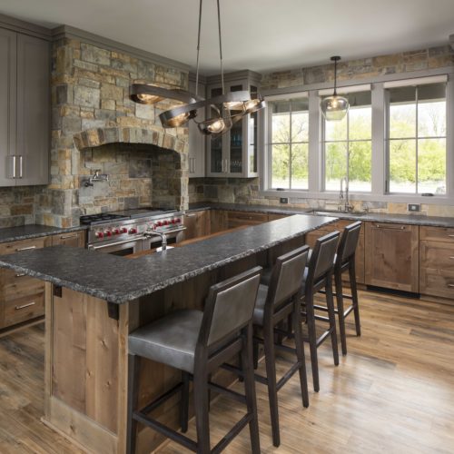 A kitchen with a stone counter top and bar stools.