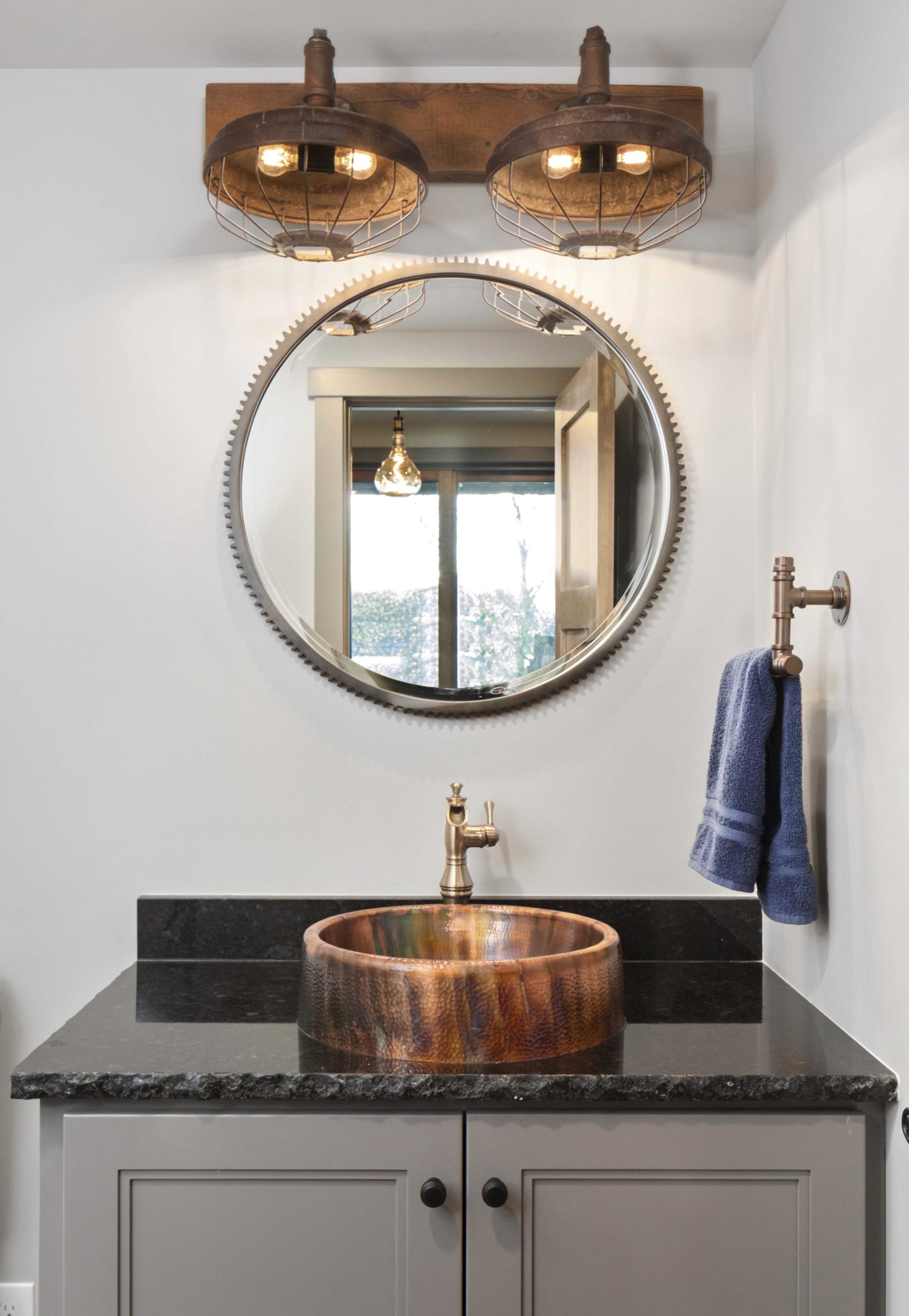 A bathroom with a copper sink and a mirror.