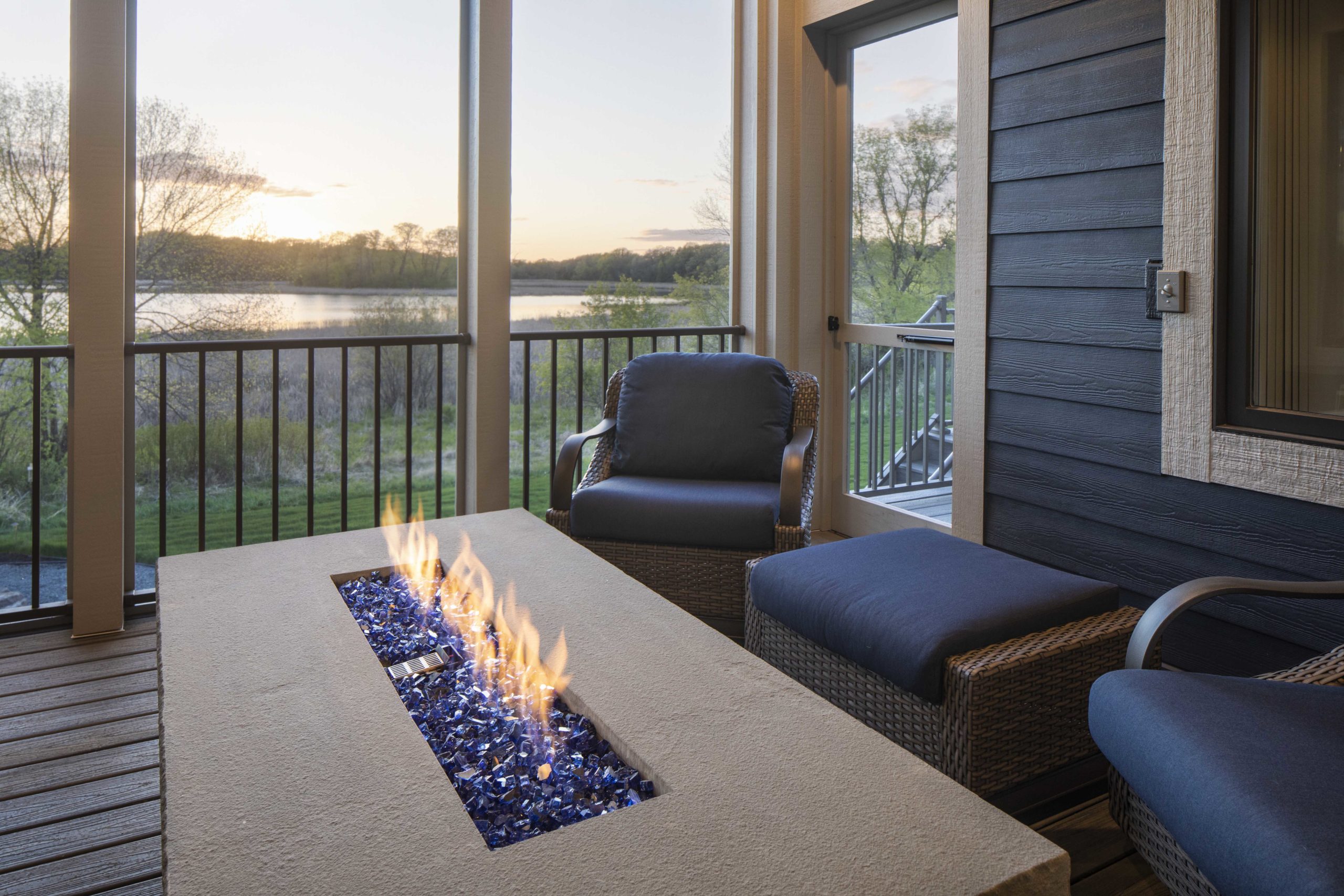 A fire pit on a deck overlooking a lake.
