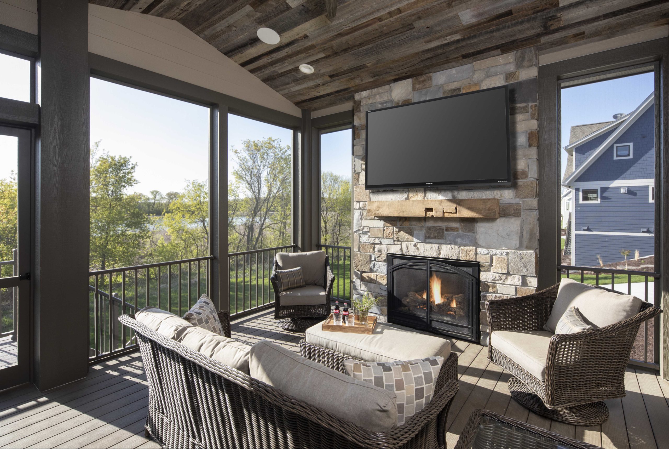 A screened in porch with a fireplace and tv.