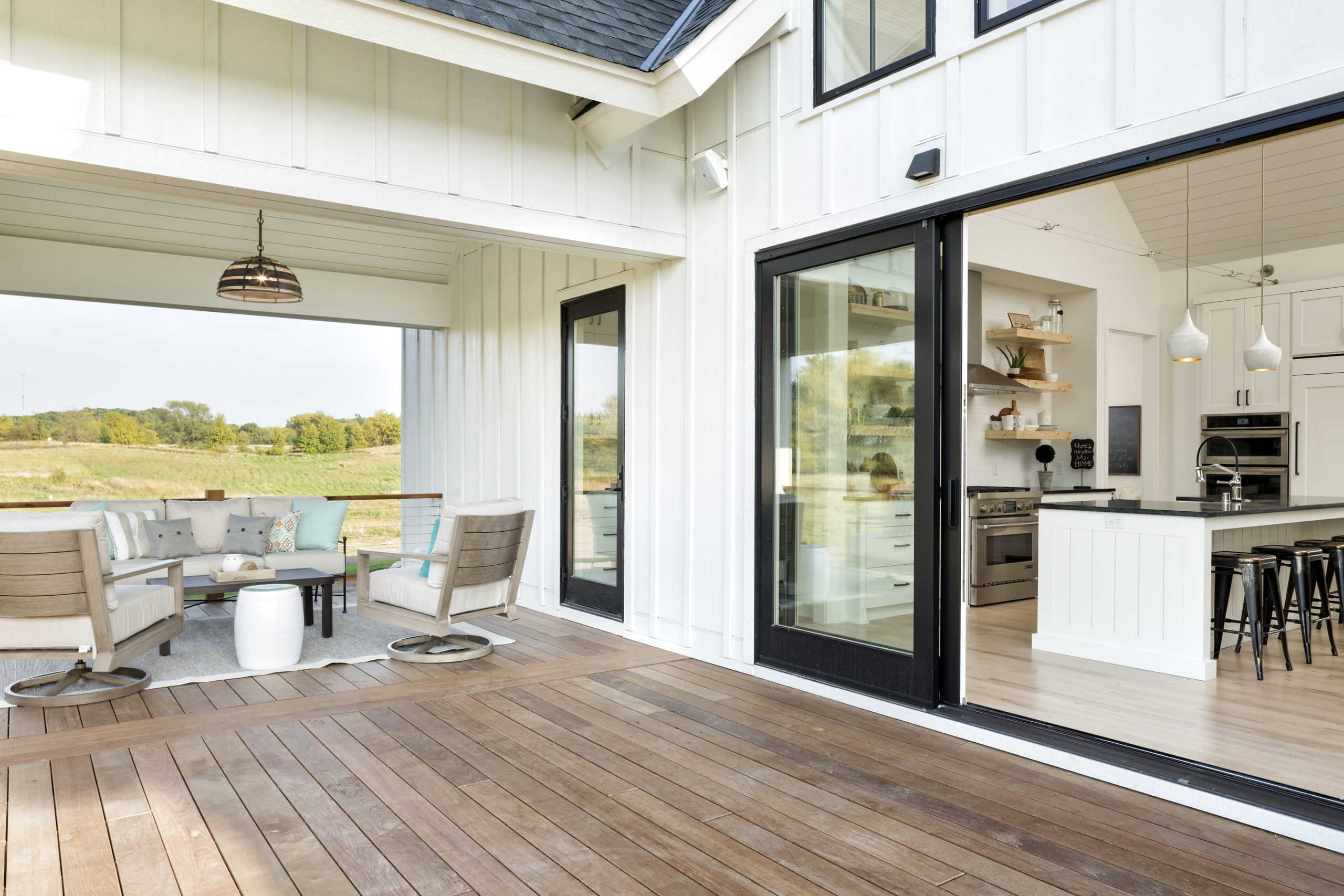 A white kitchen with a wooden deck and sliding glass doors.