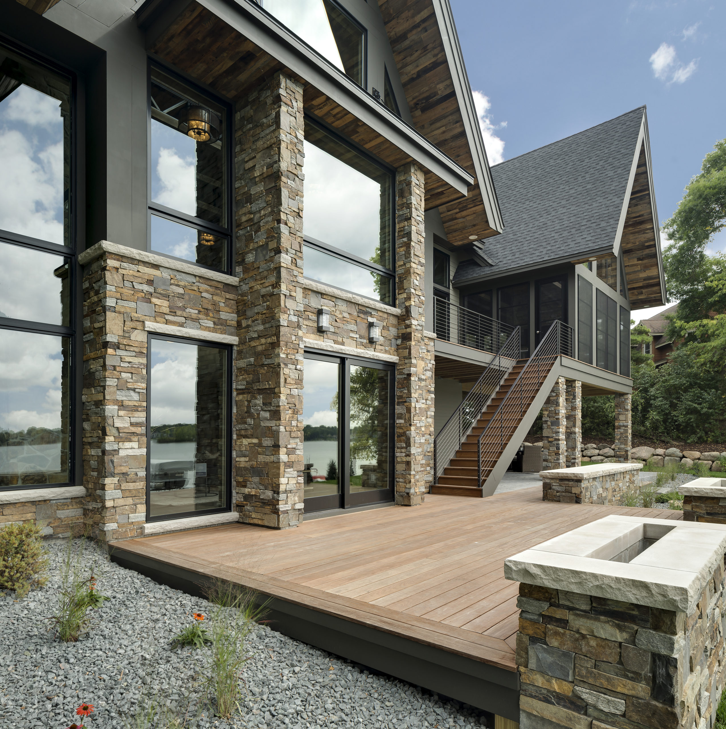 A modern home with a large deck and a view of the lake.