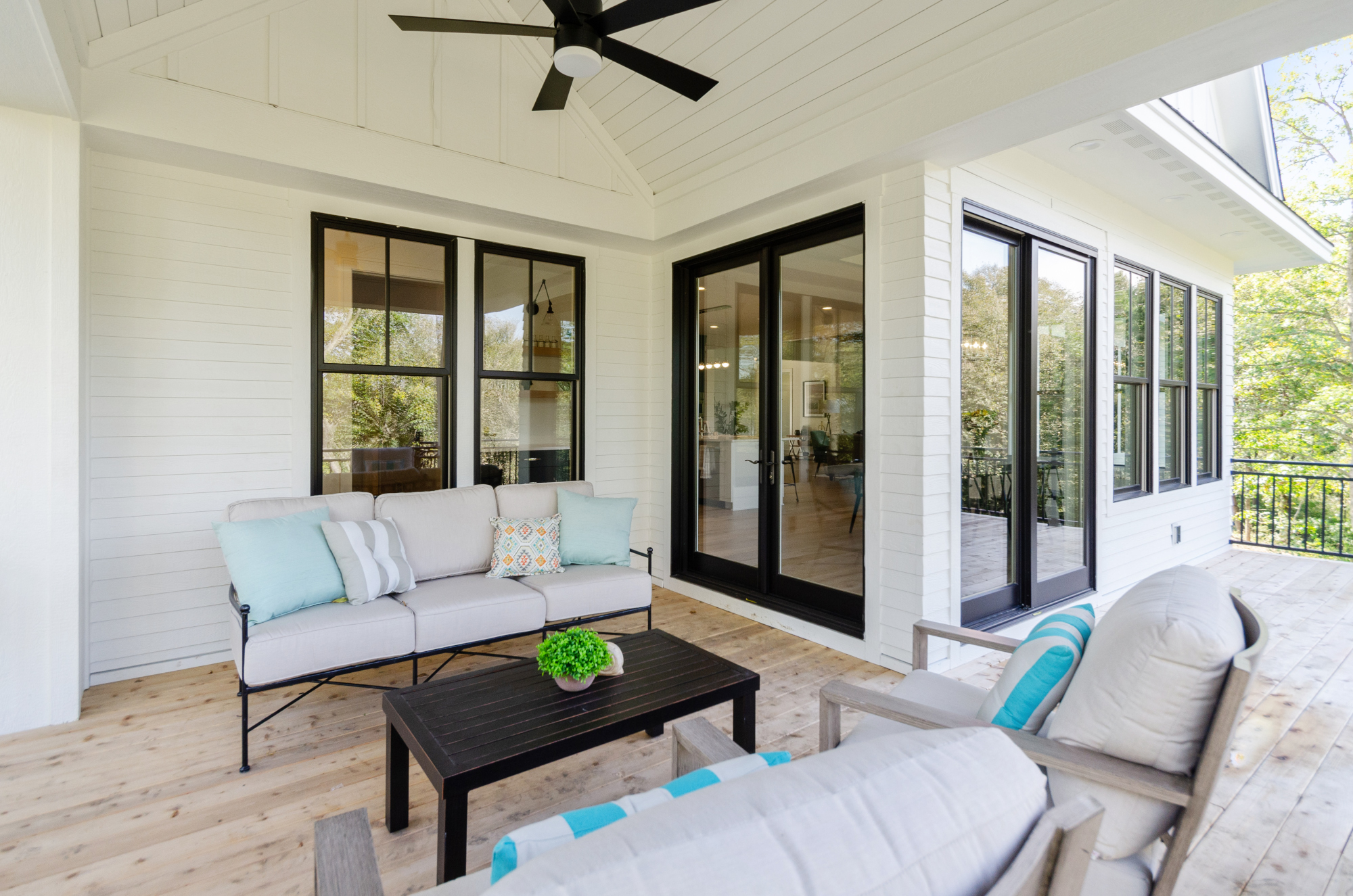 A porch with white furniture and a ceiling fan.