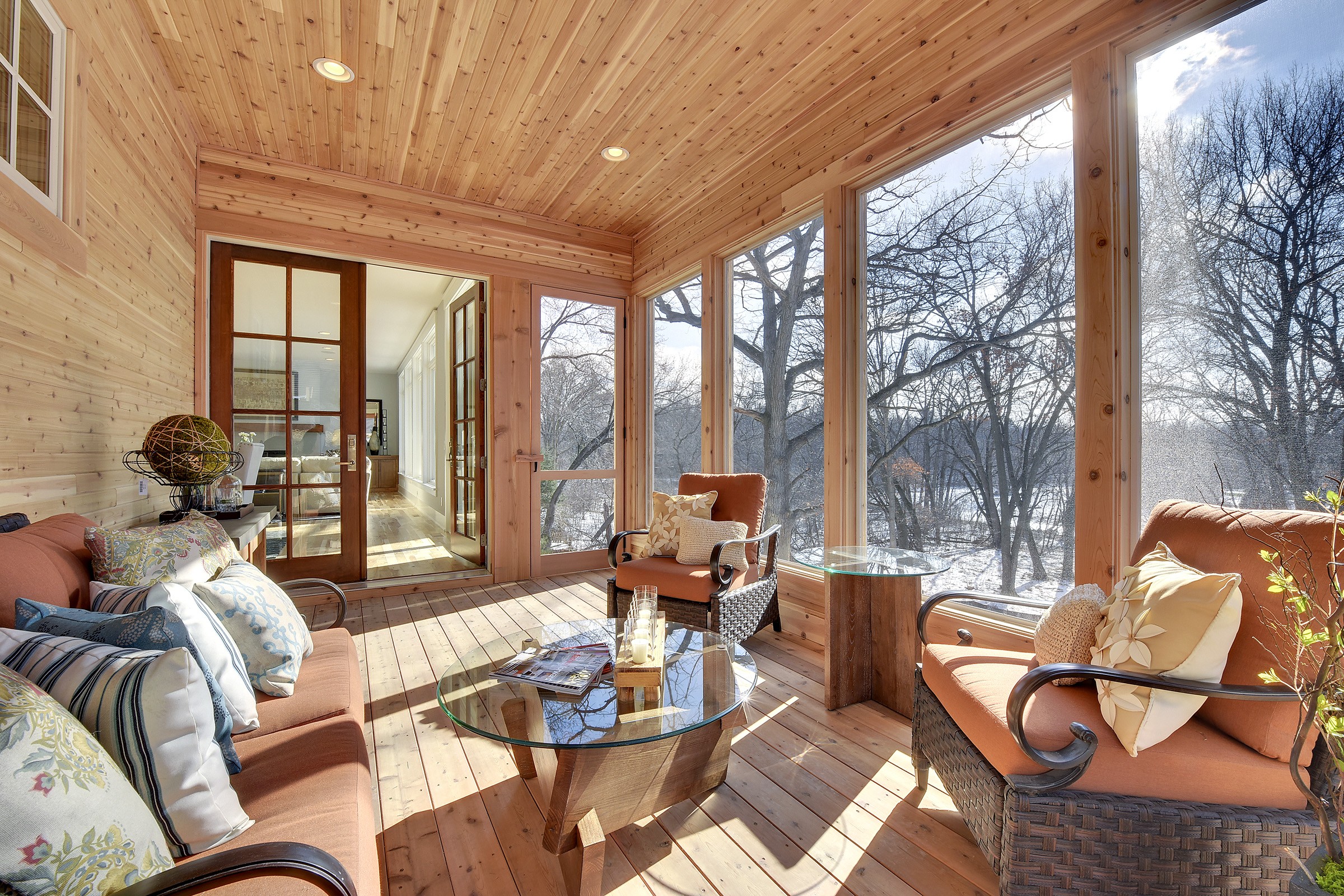 A screened in porch with furniture and a fireplace.