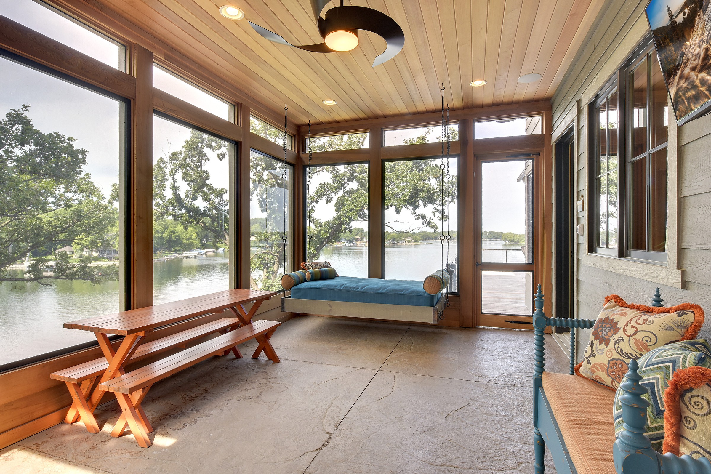 A sunroom with a bench and a view of a lake.