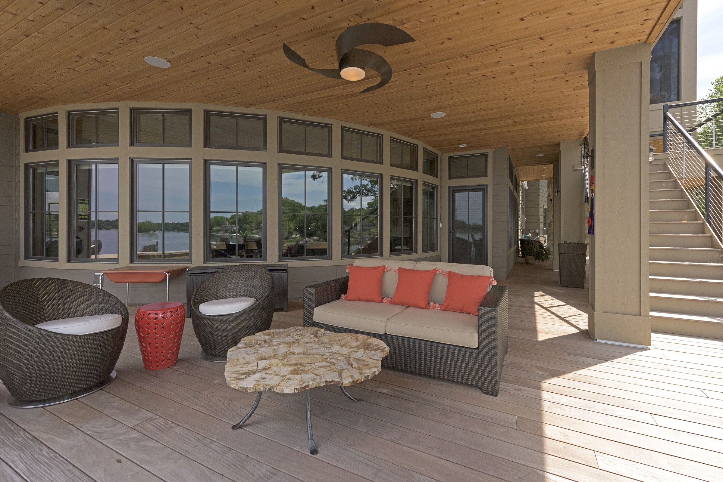 A deck with wicker furniture and a ceiling fan.
