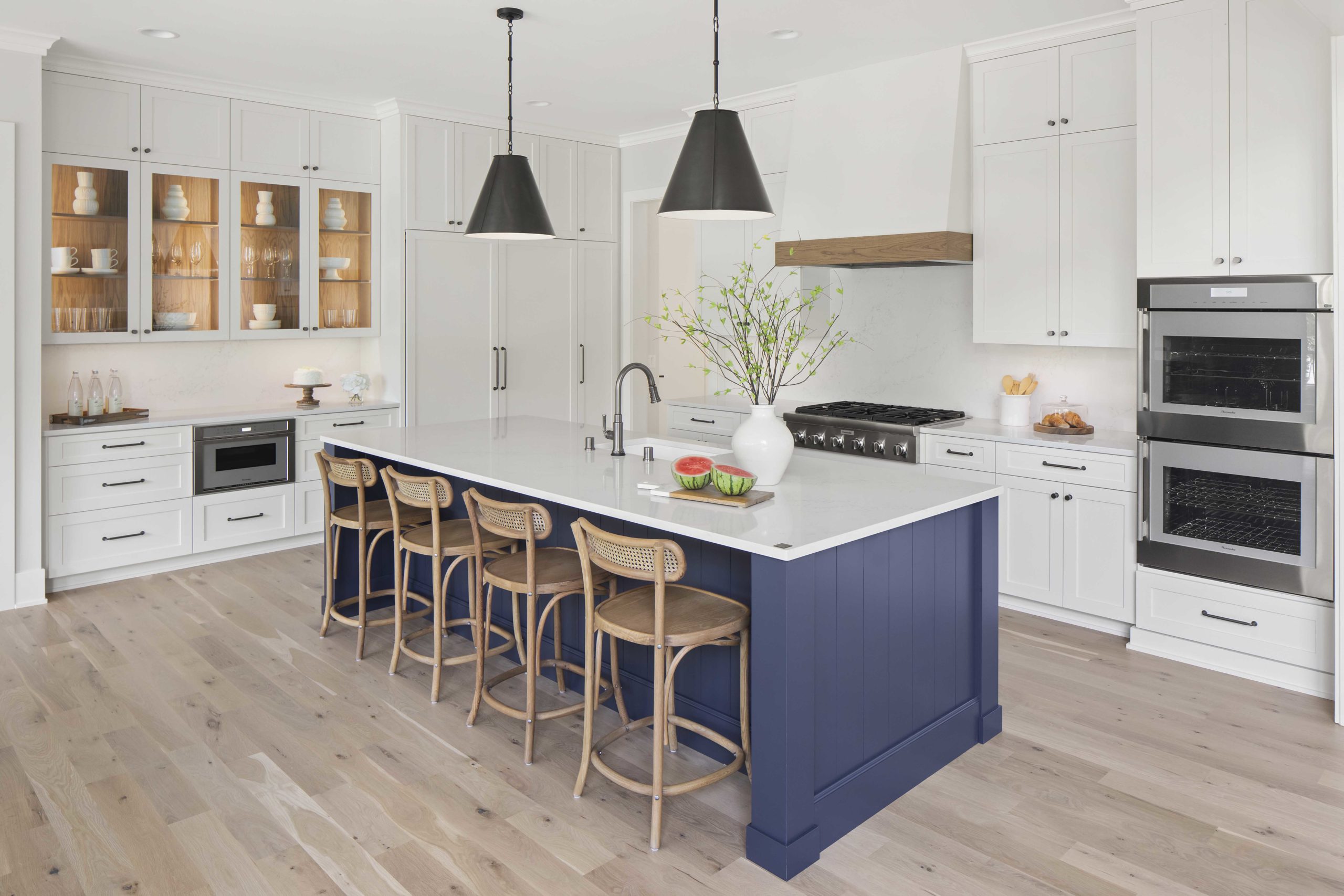 A custom lake home build with a kitchen featuring a blue island and white cabinets.