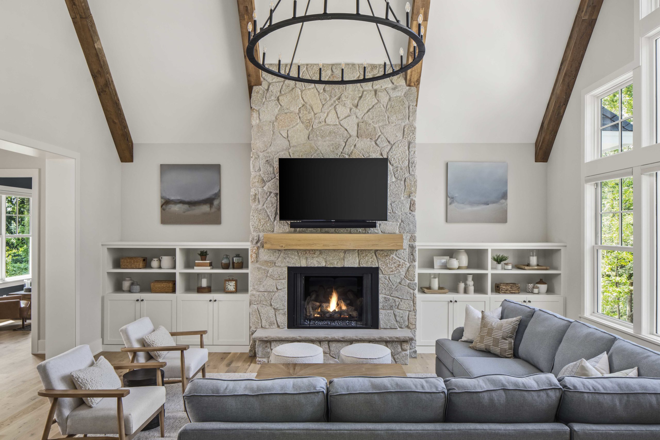 A custom lake home build with a living room featuring a stone fireplace and wooden beams.