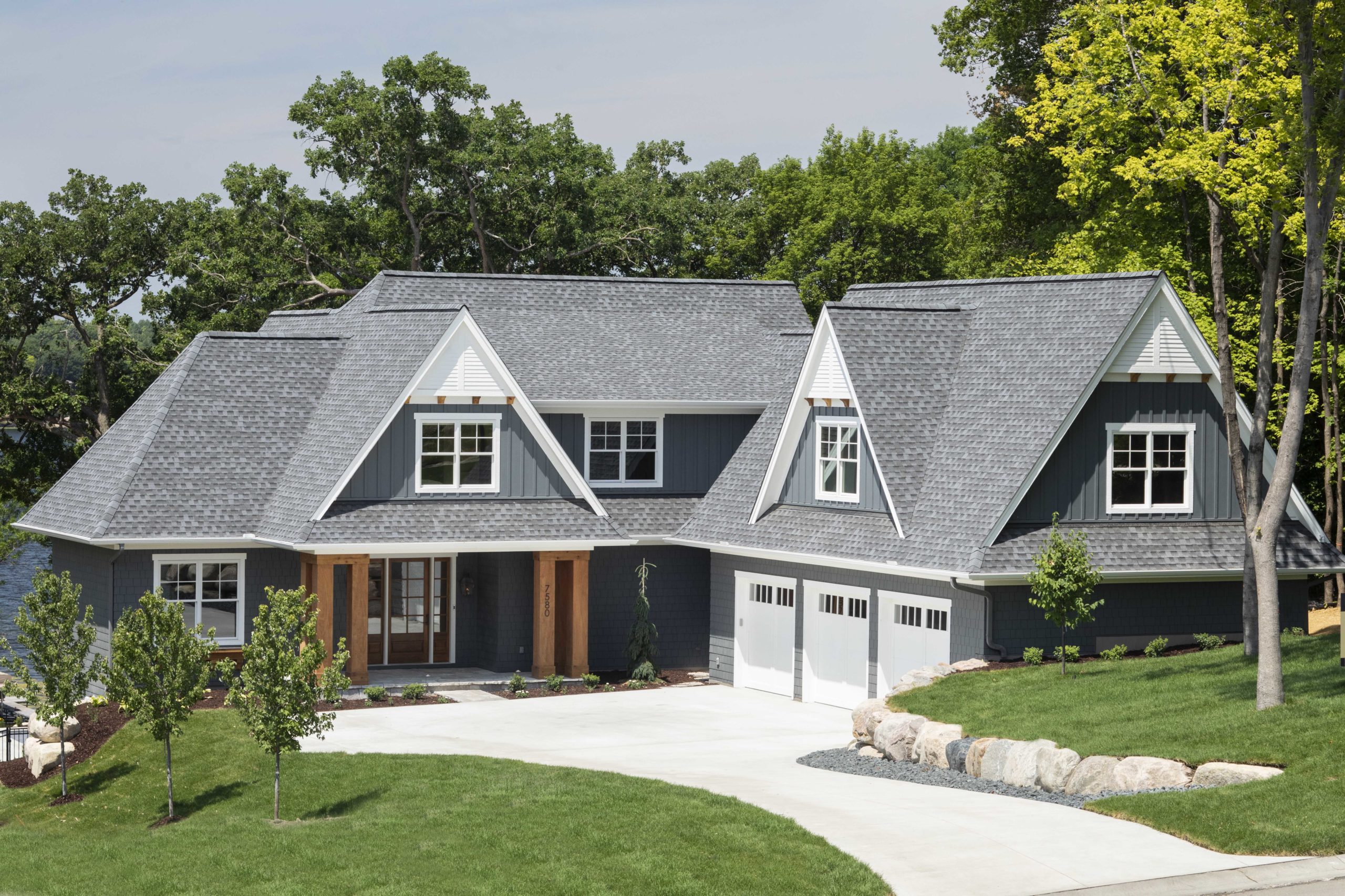 A custom lake home build with gray siding and a garage.