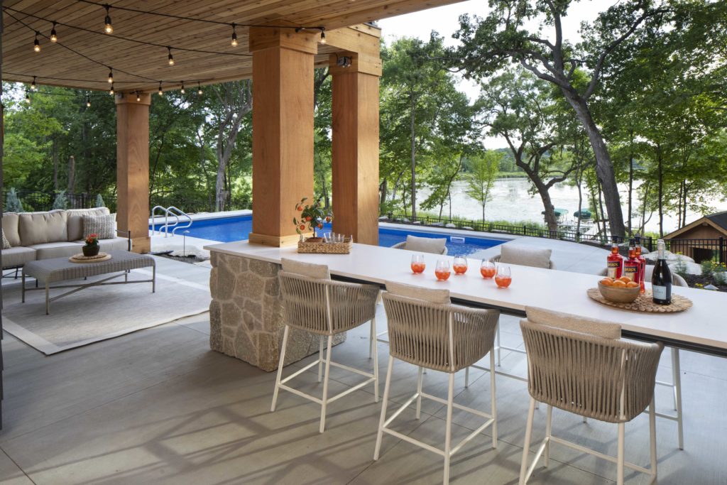 A custom lake home build featuring an outdoor bar with stools and a pool.