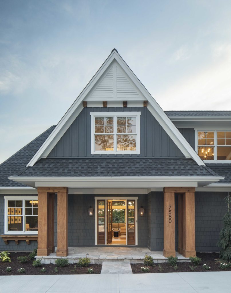 A custom lake home build featuring gray siding and wood trim.