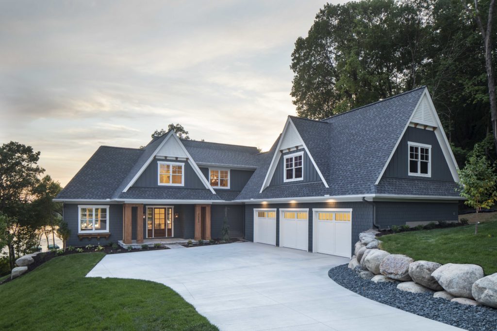 The custom lake home build boasts a stunning exterior complete with a garage and driveway.