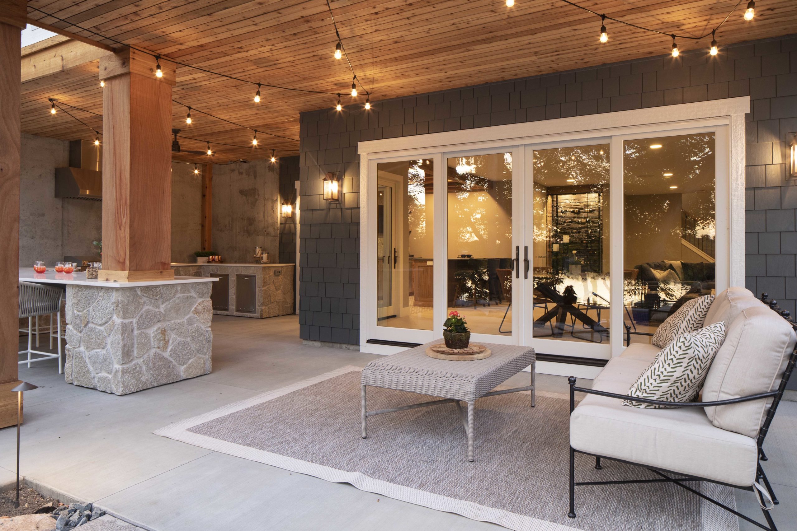 A custom lake home build with an outdoor living area featuring a fireplace and string lights.