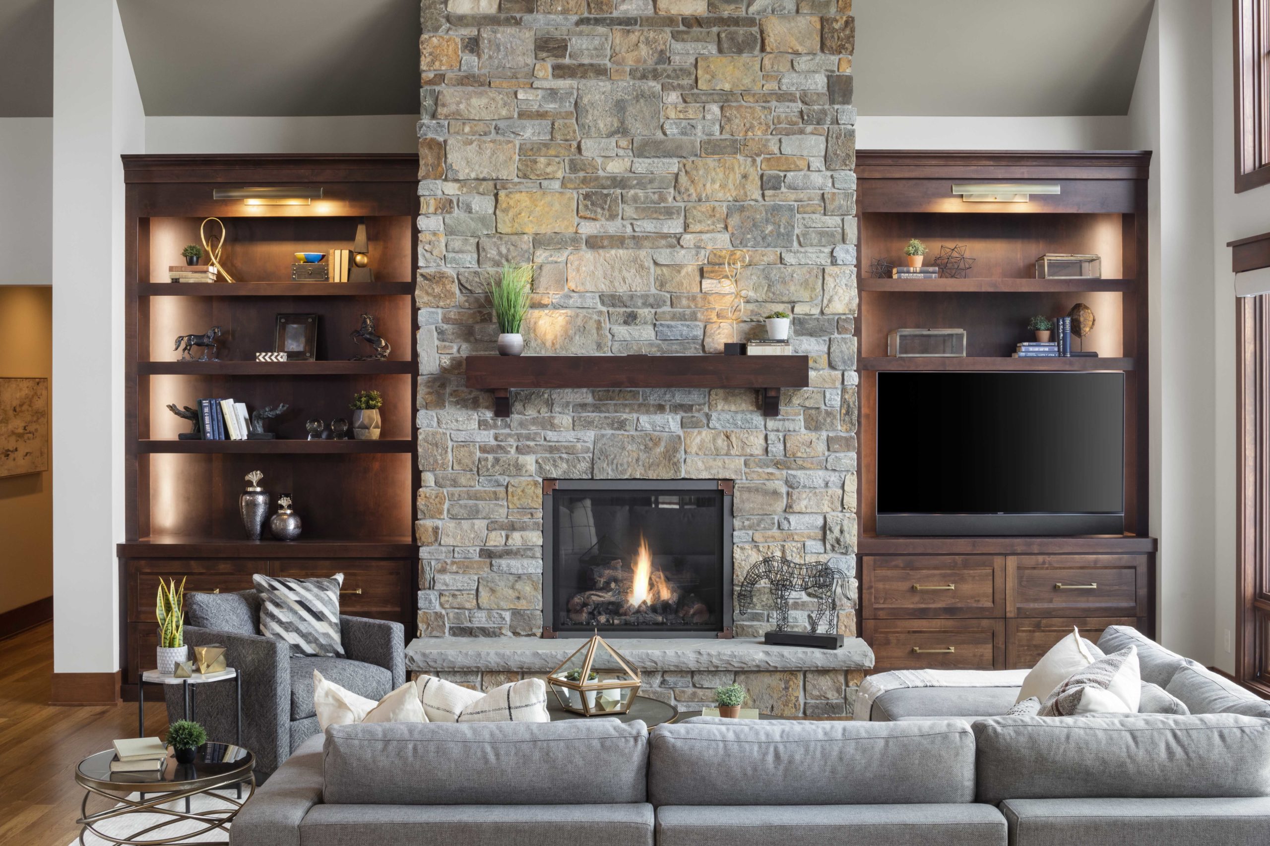 A custom home remodel featuring a living room with a stone fireplace and TV.