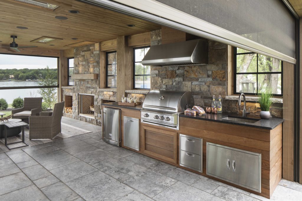 A custom home remodel featuring an outdoor kitchen with a grill and a fireplace.