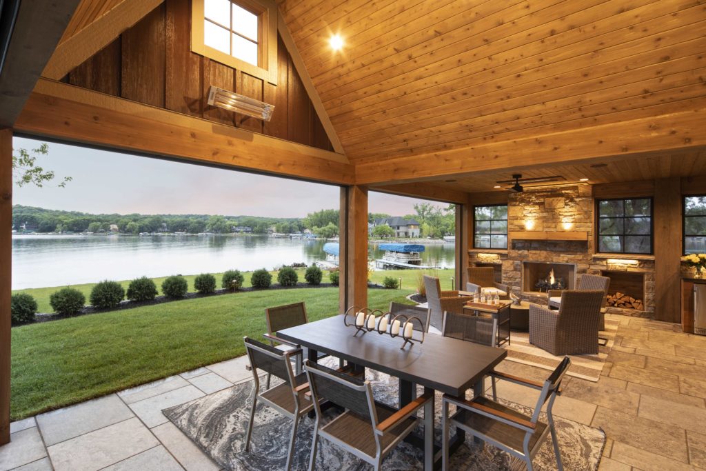 A custom home remodel with an outdoor dining area overlooking a serene lake.