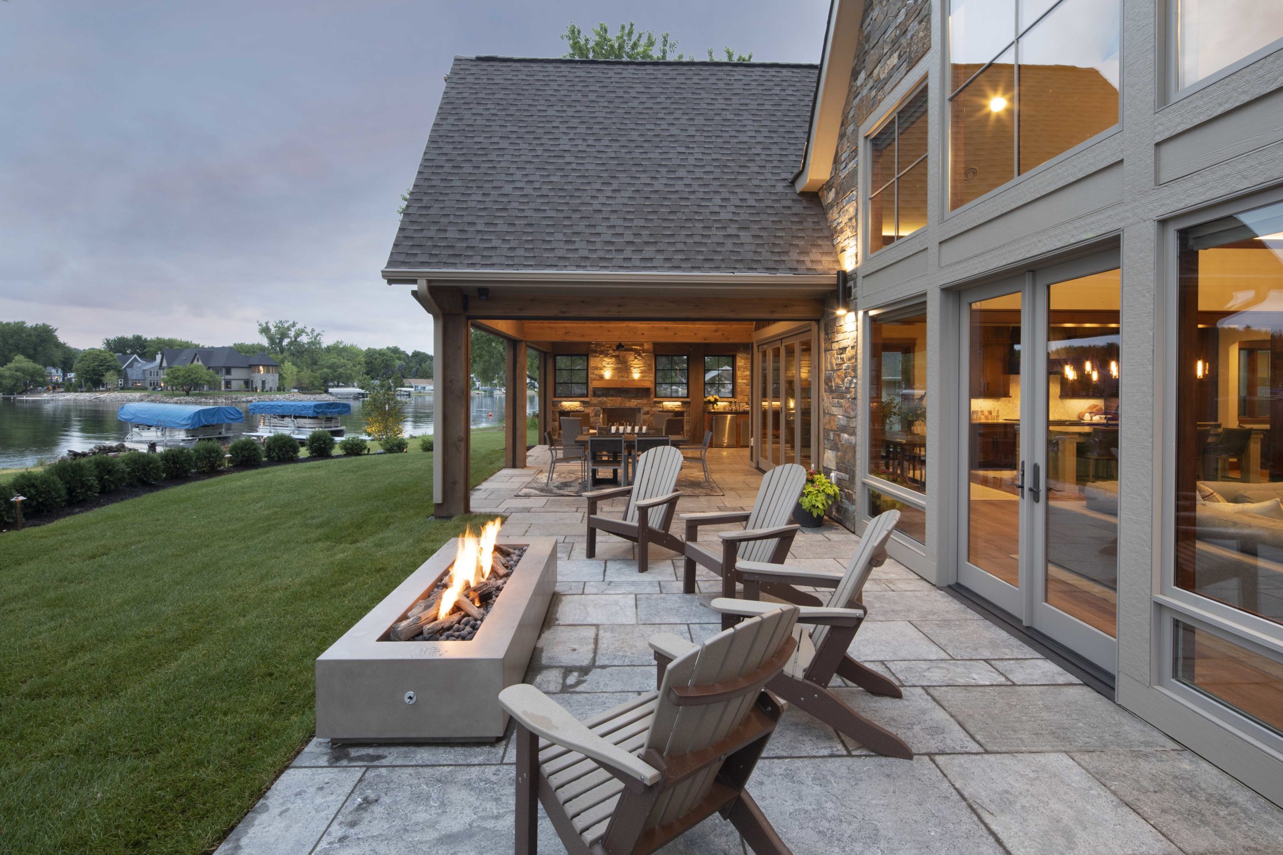 A custom home with a patio featuring a fire pit and a stunning view of the lake.