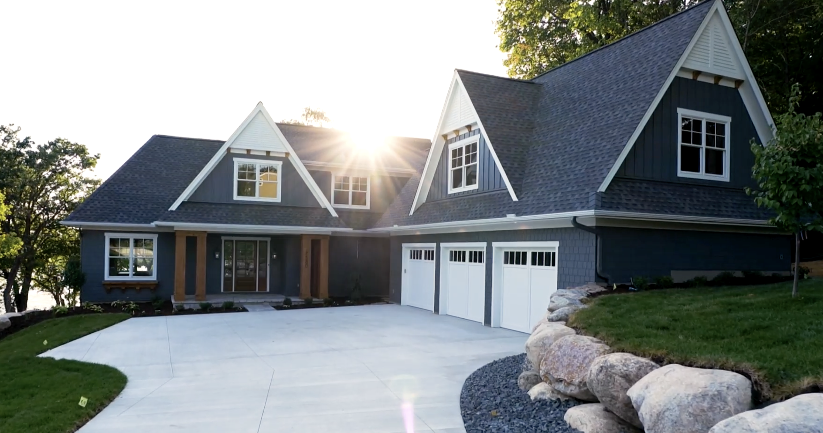 A custom lake home build with a large driveway and garage.