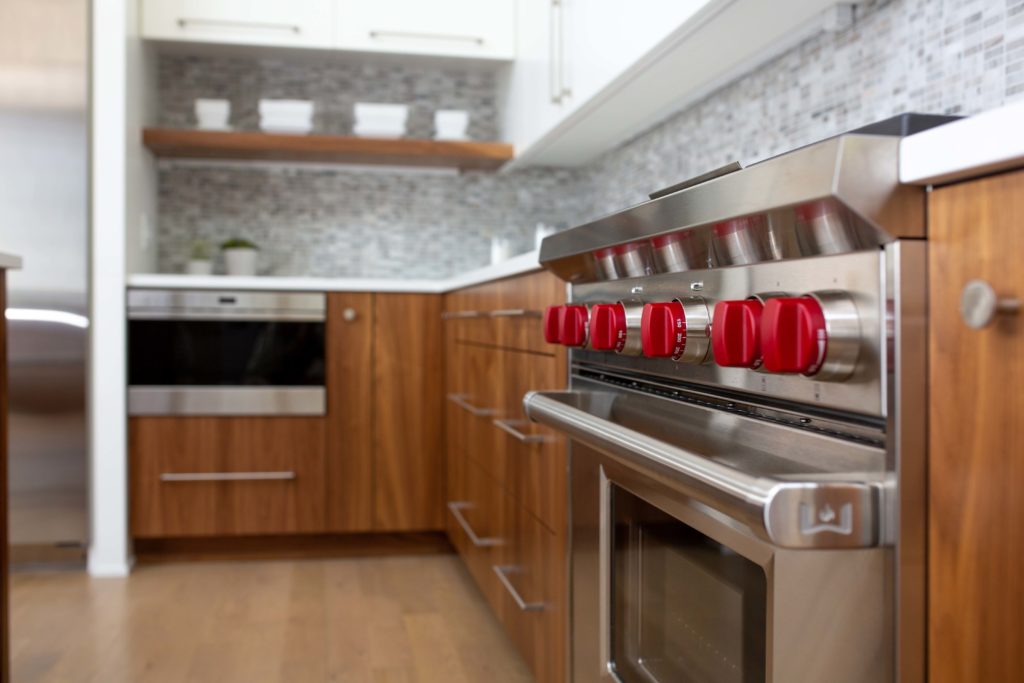 A modern stainless steel stove with red knobs in a lake home build.